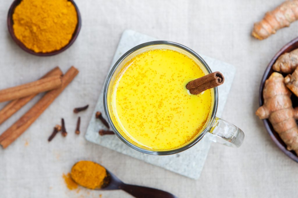 5 Steps for Healing Bloating & Constipation in Eating Disorders | bloating Turmeric drink latte tea milk with cinnamon in a glass mug with fresh and dried turmeric bloating - Turmeric drink, latte, tea, milk with cinnamon in a glass mug with fresh and dried turmeric