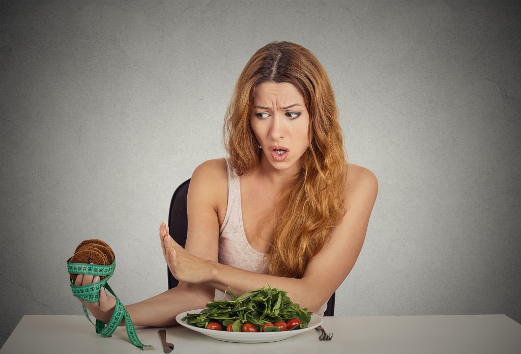10 Most Unbelievable Metabolism Myths That You Should Know By Now | metabolism myths young woman deciding whether to eat healthy food or sweet cookies metabolism myths - young woman deciding whether to eat healthy food or sweet cookies