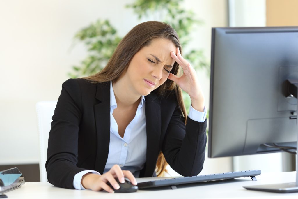 Hormone Imbalance 101: 4 Little-Known Causes Your Doctor Didn’t Tell You About | hormone imbalance woman suffering headache at work using a desktop computer in the office hormone imbalance - woman suffering headache at work using a desktop computer in the office