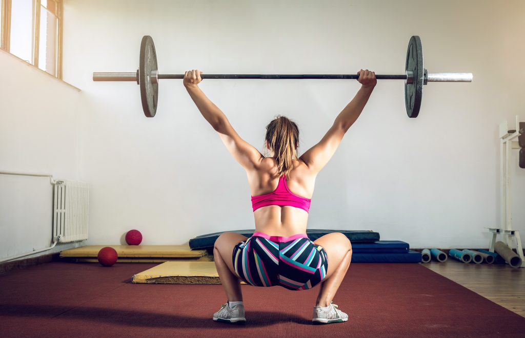 How to Get a Flat Stomach & Toned Muscles Without Starving or Over Exercising | How to get a flat stomach girl doing heavy duty squats in gym with barbell How to get a flat stomach - girl doing heavy duty squats in gym with barbell