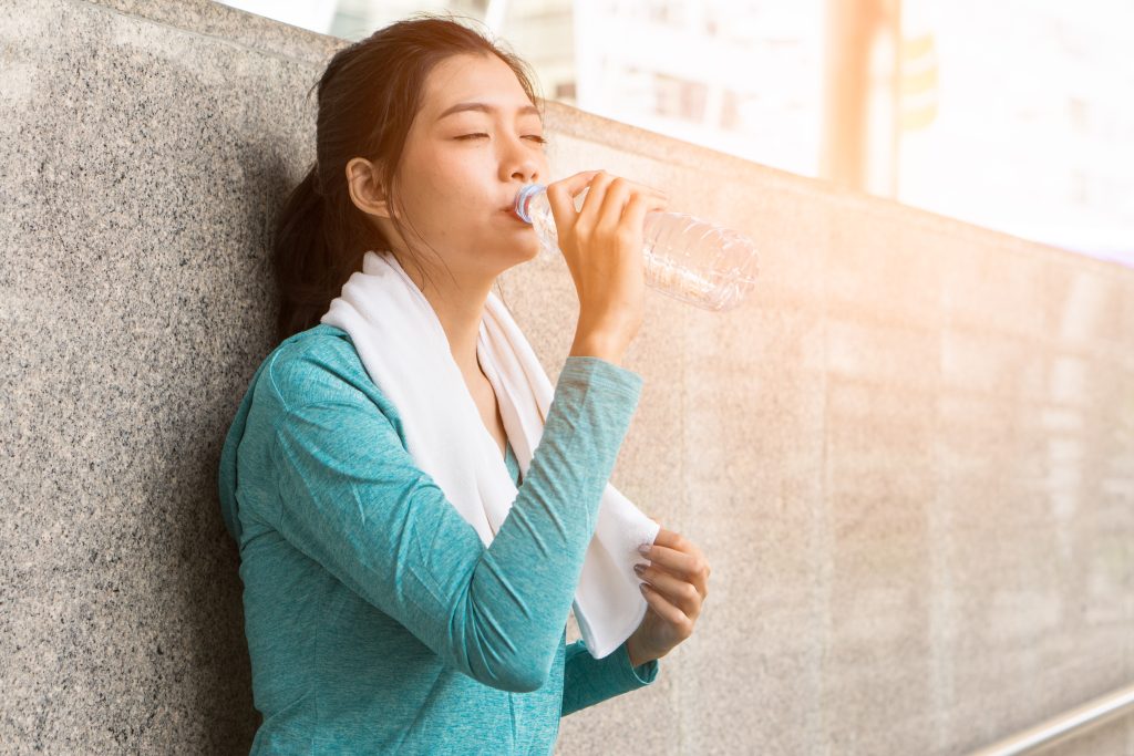 How to Get a Flat Stomach & Toned Muscles Without Starving or Over Exercising | How to get a flat stomach woman drinking water to rehydrate to avoid heat stroke after running outdoors How to get a flat stomach - woman drinking water to rehydrate to avoid heat stroke after running outdoors