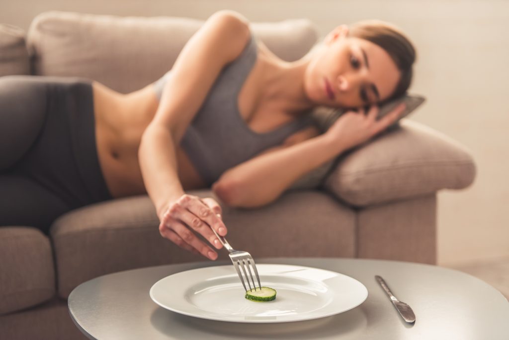 Holistic Treatment for Eating Disorders: 13 Essentials for Holistic Eating Disorder Recovery | eating disorder recovery Slice of cucumber on the plate in the foreground depressed girl lying in the sofa eating disorder recovery - Slice of cucumber on the plate in the foreground, depressed girl lying in the sofa