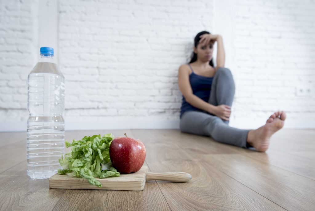 Holistic Treatment for Eating Disorders: 13 Essentials for Holistic Eating Disorder Recovery | eating disorder recovery teenager girl sitting on ground alone and worried at home suffering nutrition and eating disorder eating disorder recovery - teenager girl sitting on ground alone and worried at home suffering nutrition and eating disorder