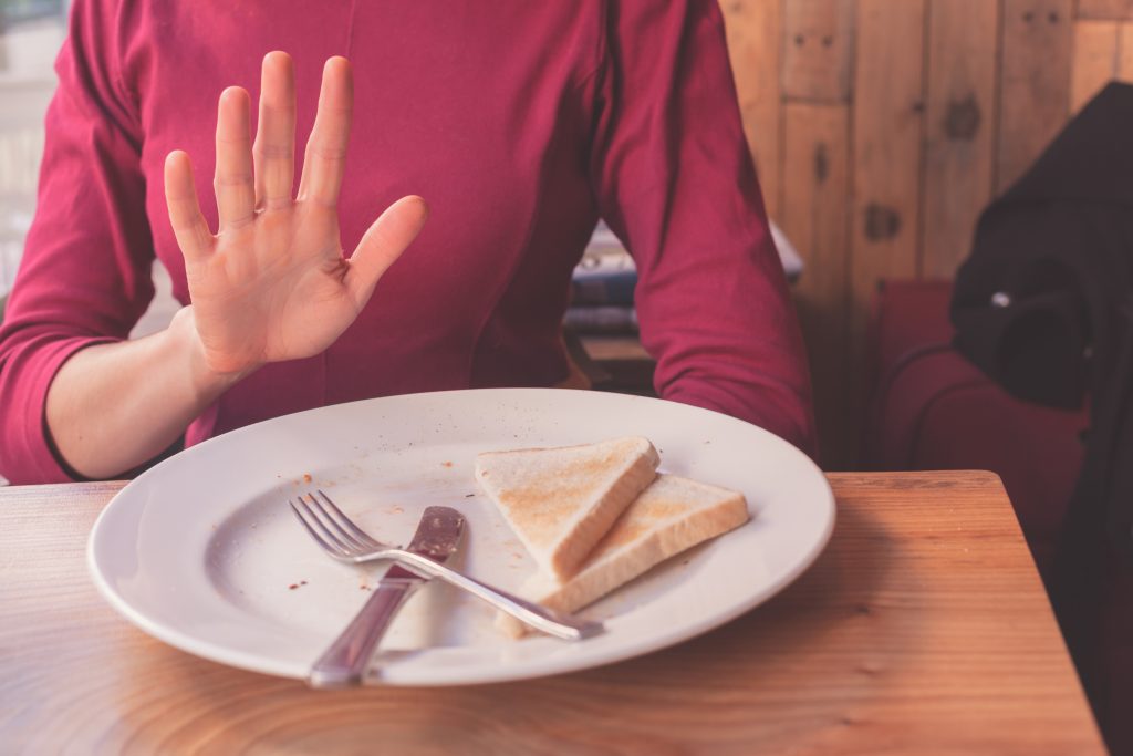 Have You Accidentally Eaten Foods That Cross-React with Gluten? Avoid These Top 10 Triggers | foods that cross react with gluten A woman on a gluten free diet is saying no thanks to toast 1 foods that cross-react with gluten - A woman on a gluten free diet is saying no thanks to toast