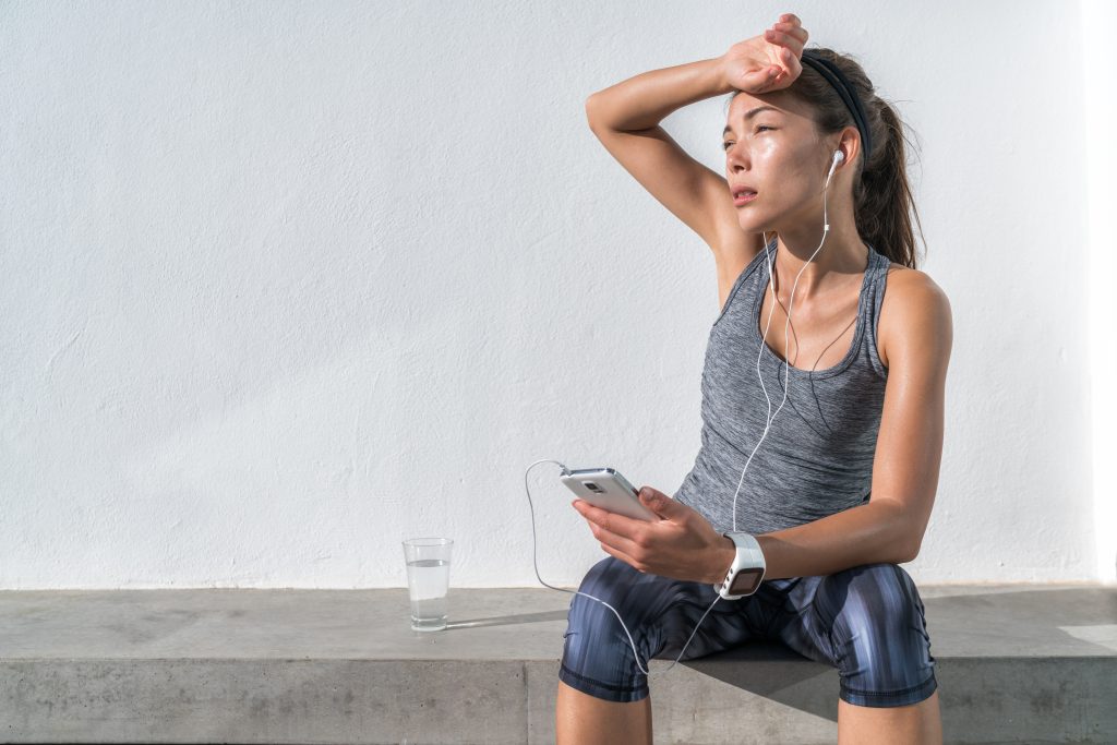 Why Do I Feel Like This? A Total Gut-Brain Reset Journey | total gut brain reset Tired fitness woman sweating taking a break listening to music on phone after difficult training total gut-brain reset - Tired fitness woman sweating taking a break listening to music on phone after difficult training